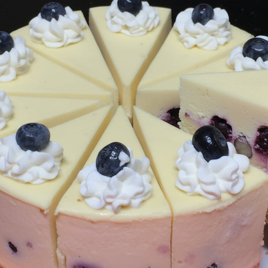 Close-up of a sliced cake with blueberries and cream on a dark surface